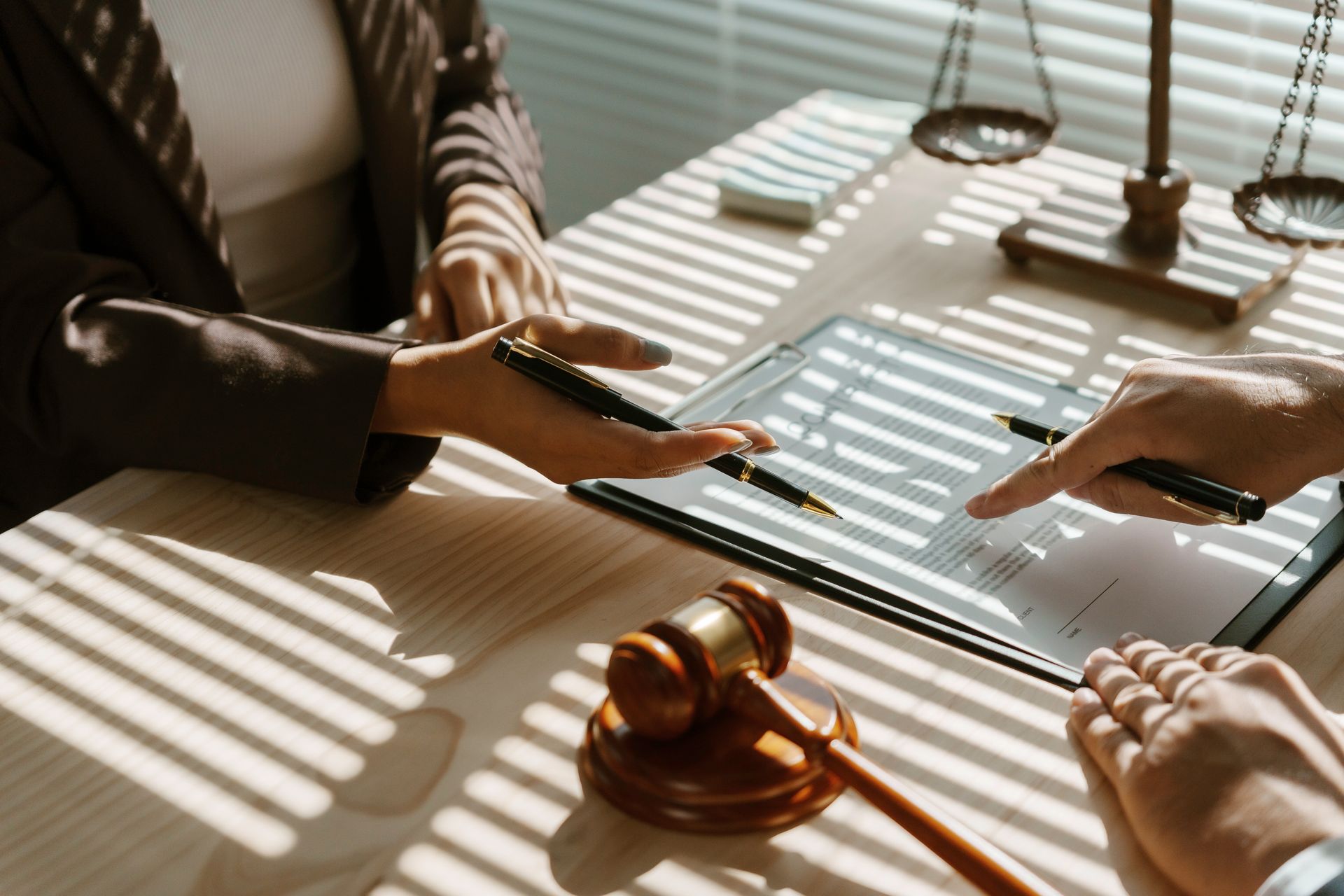 Une avocate tenant un stylo dans les mains présente une convention d'honoraires à un client.