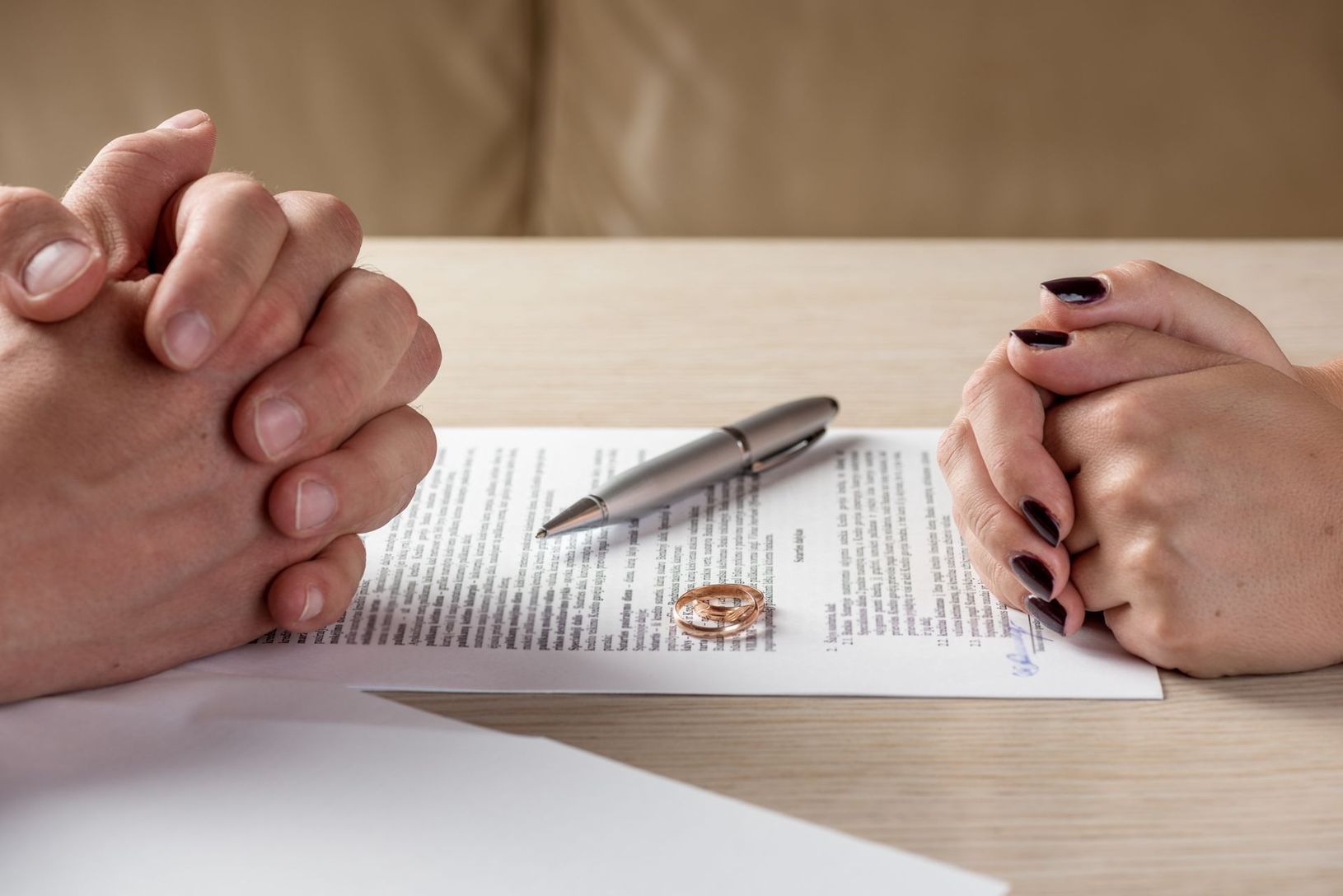 Deux personnes se tiennent la main au-dessus d'un document signé, un stylo posé sur une table.