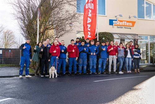 Eine Gruppe von Menschen posiert vor einem Gebäude für ein Foto.