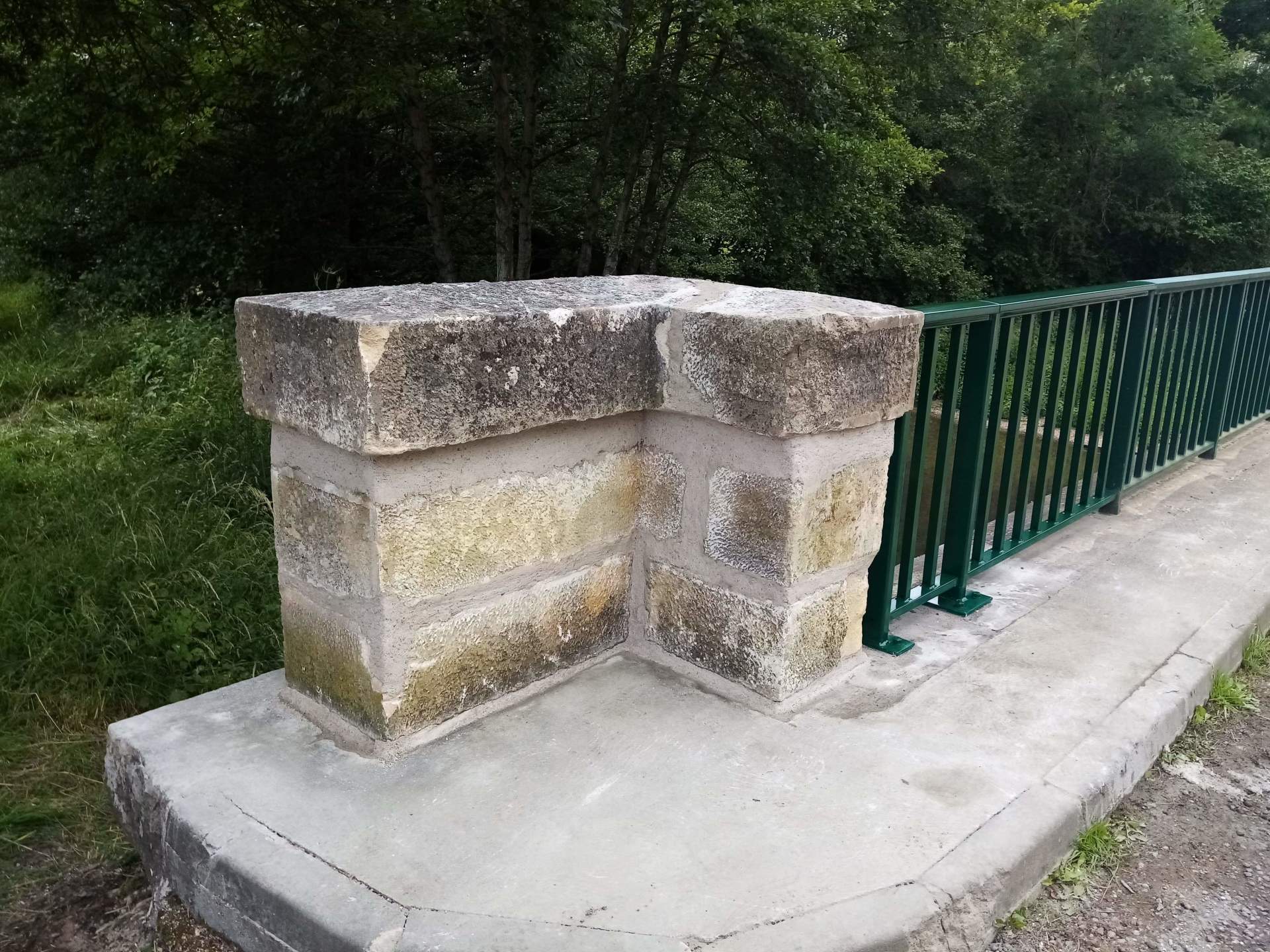 Mur en pierre avec une rampe et une clôture verte