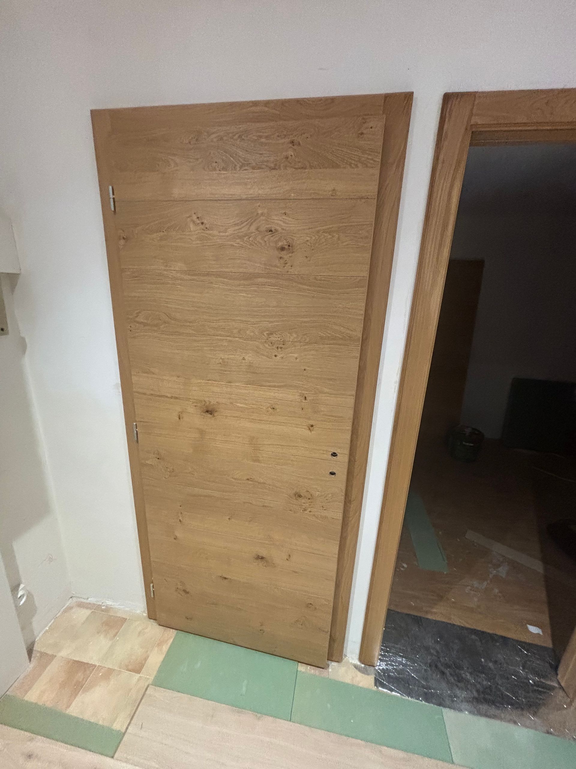 Une porte en bois appuyée contre un mur pendant les travaux, révélant une ouverture inachevée.