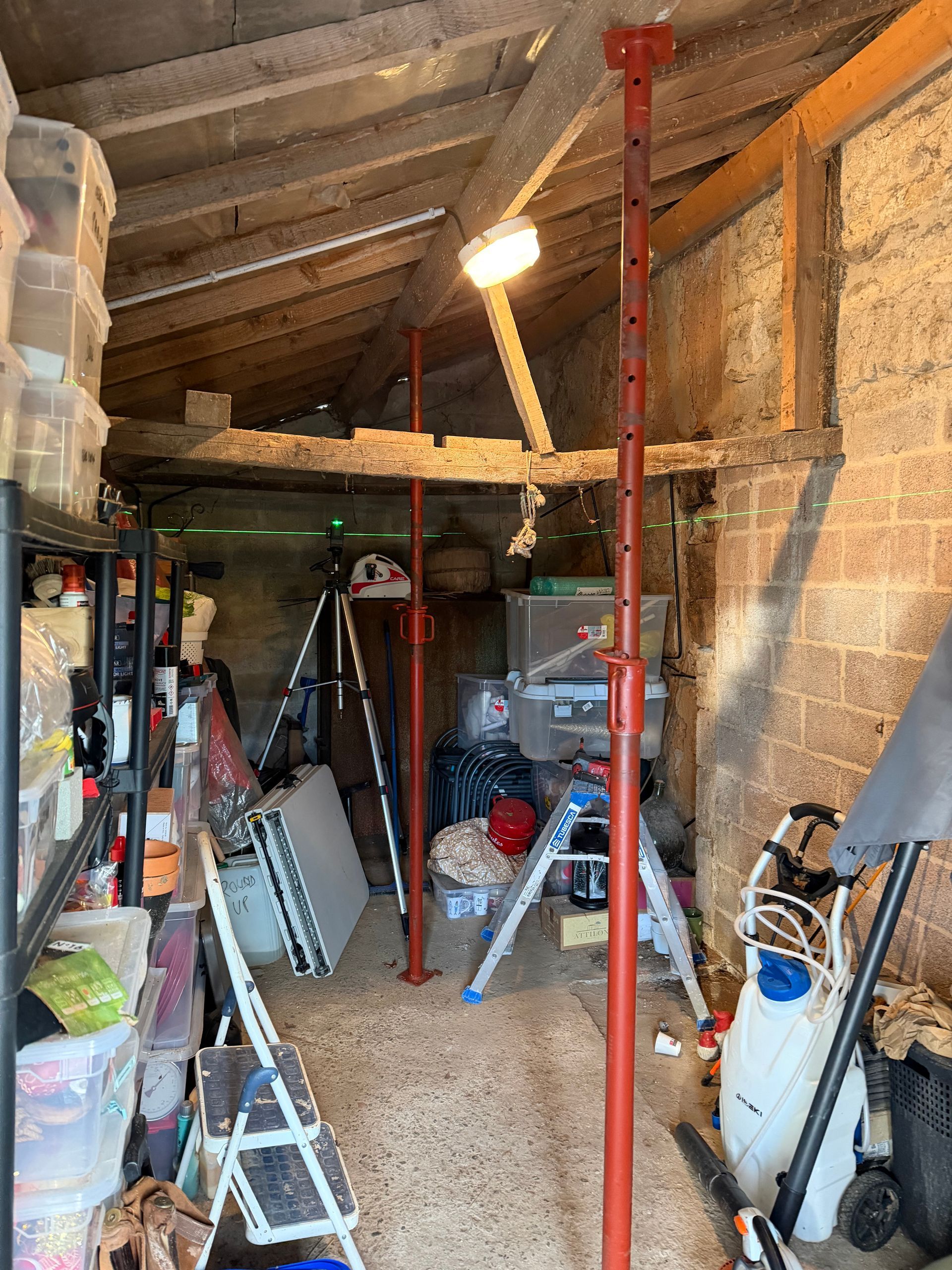 Des poteaux de soutien rouges, à l'intérieur d'un hangar encombré, soutiennent une poutre.