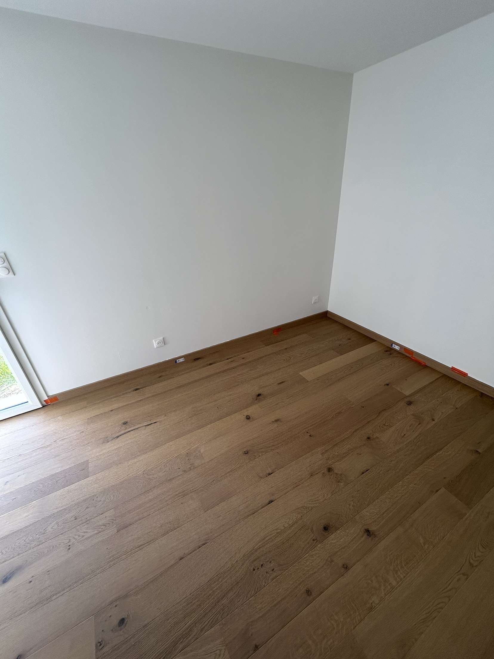Chambre avec parquet clair et murs blancs