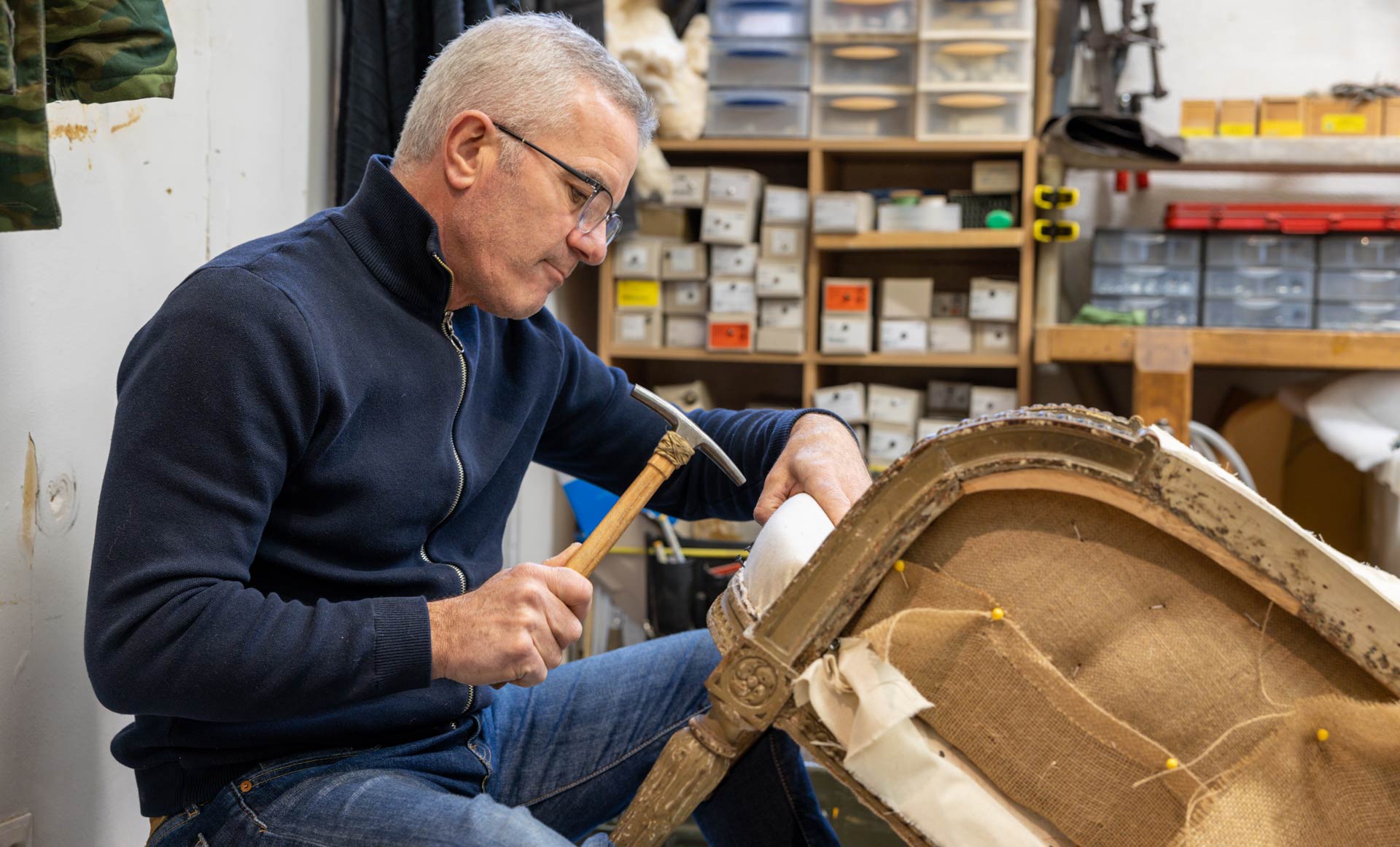 Un tapissier pendant la réfection d'un fauteuil