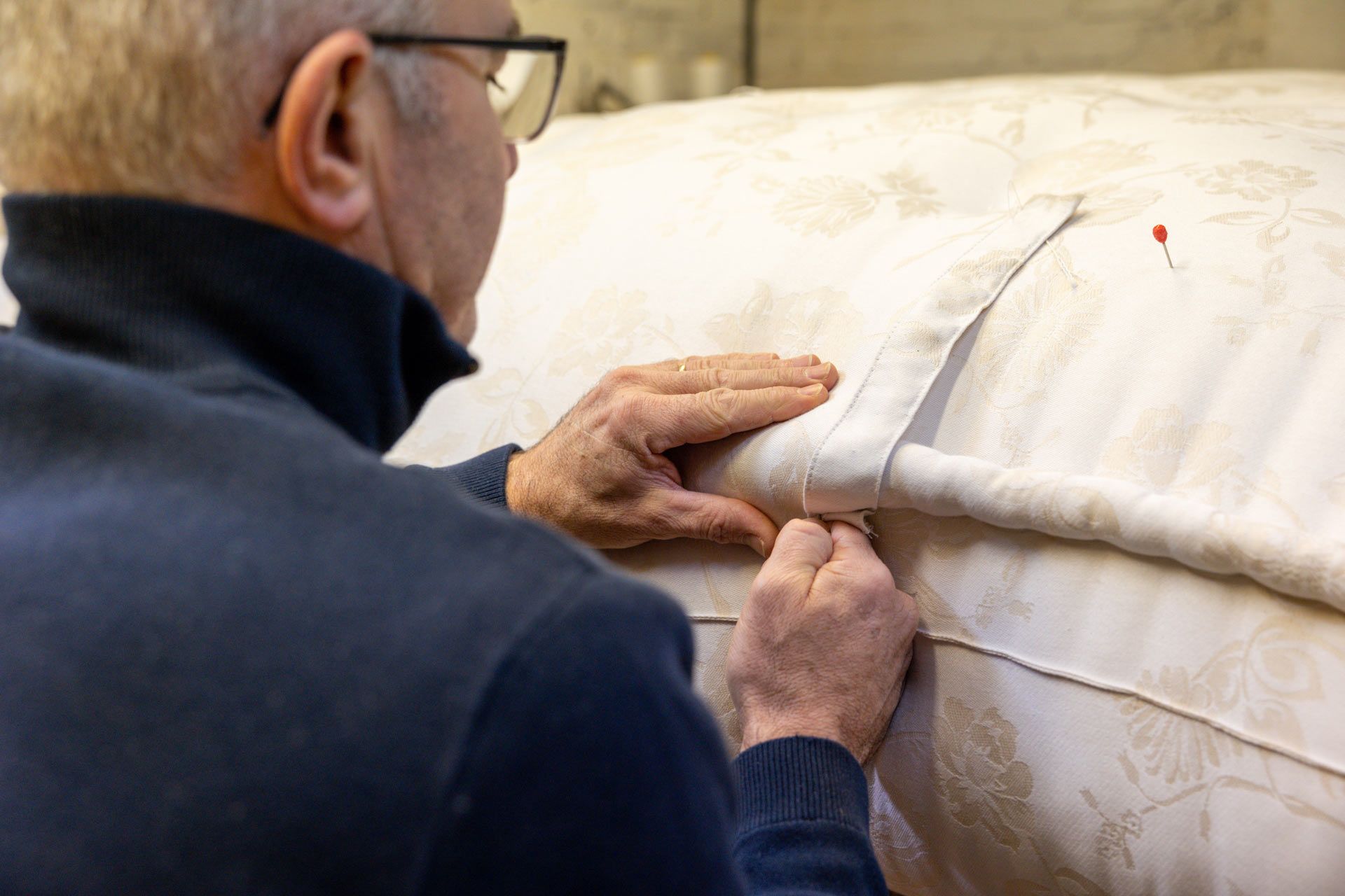Un tapissier pendant la couture d'un matelas artisanal fait main