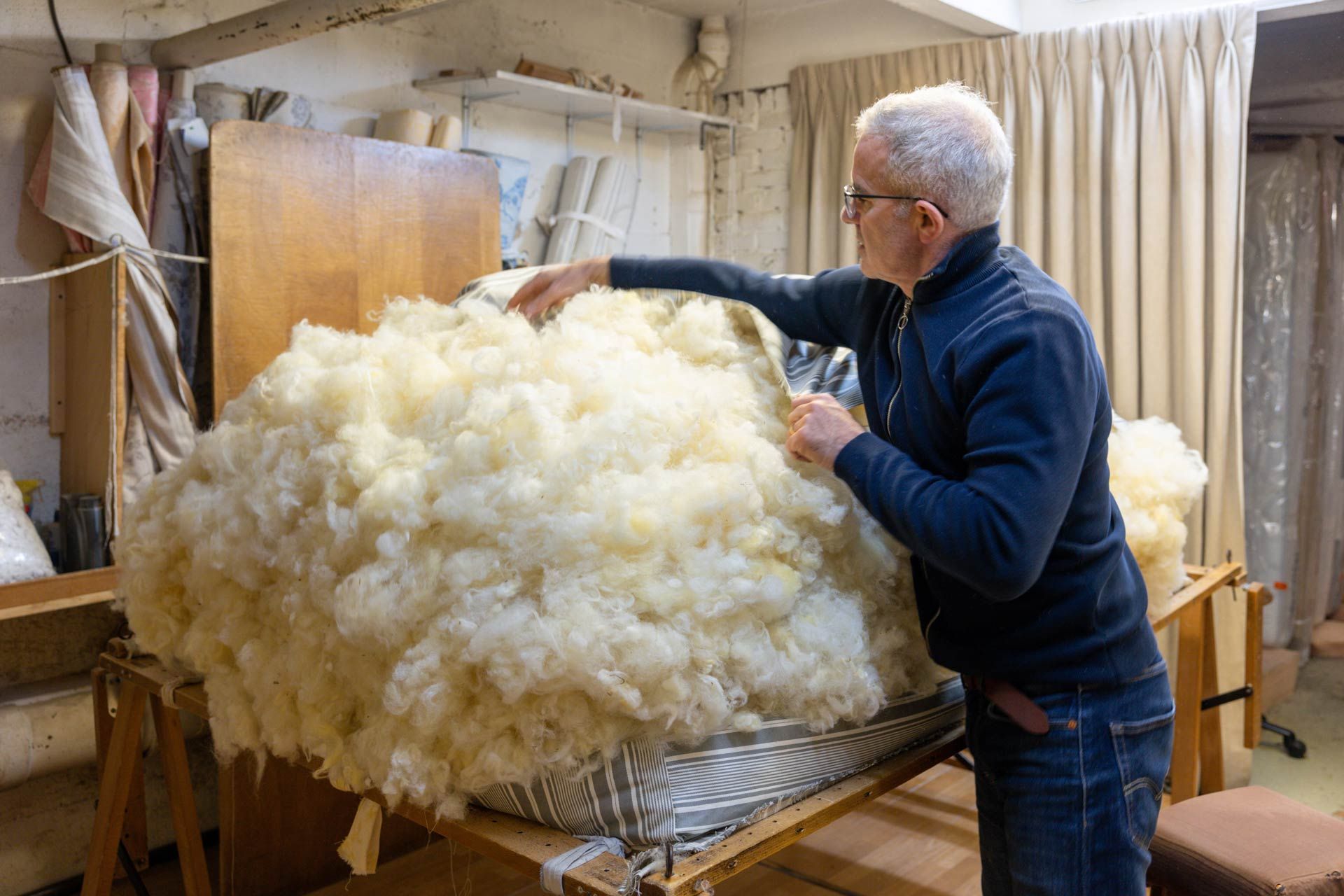 Un tapissier garnissant de laine un matelas traditionnel