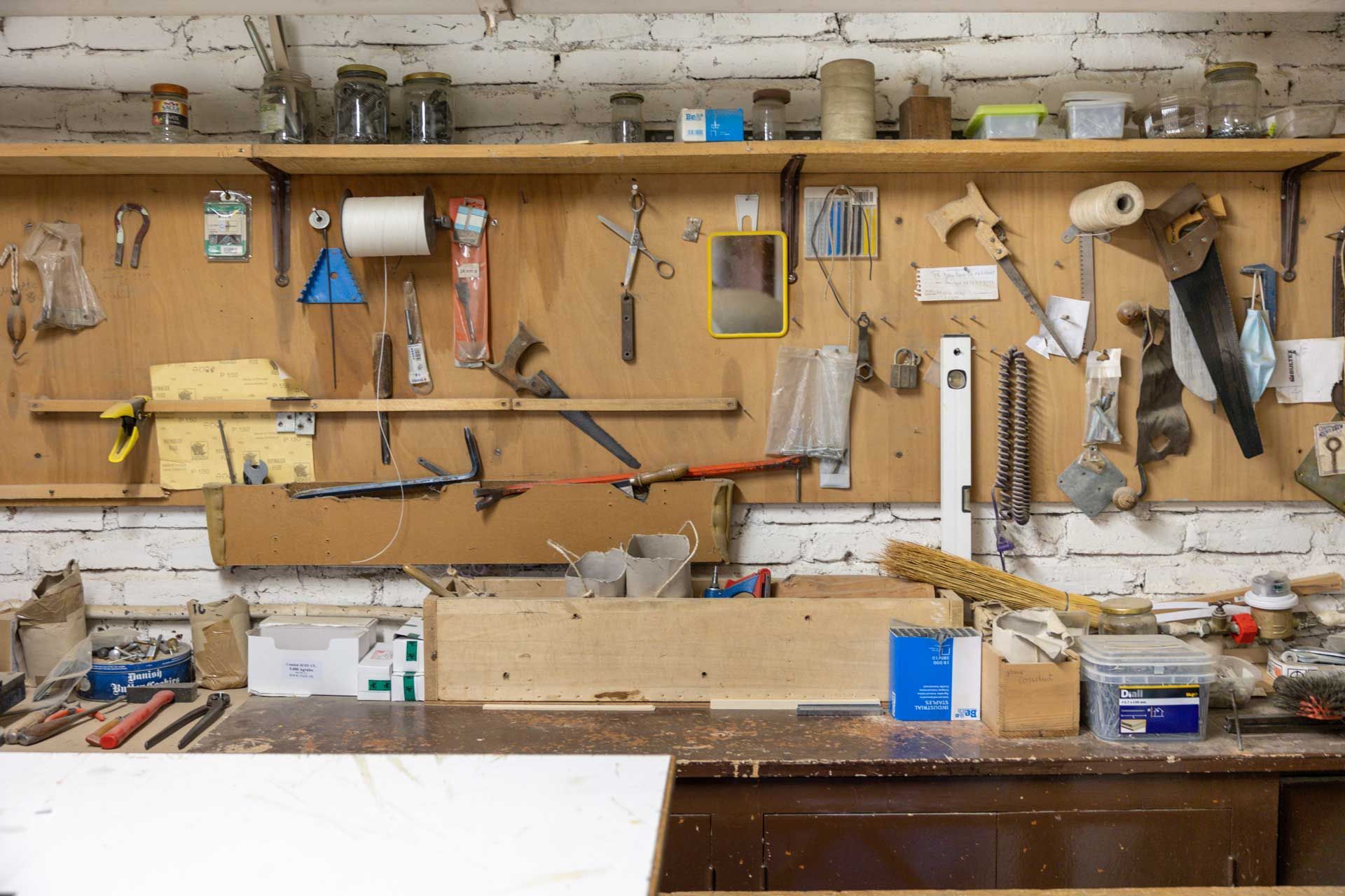 Un établi avec un pan de mur où sont accrochés les outils de tapissier