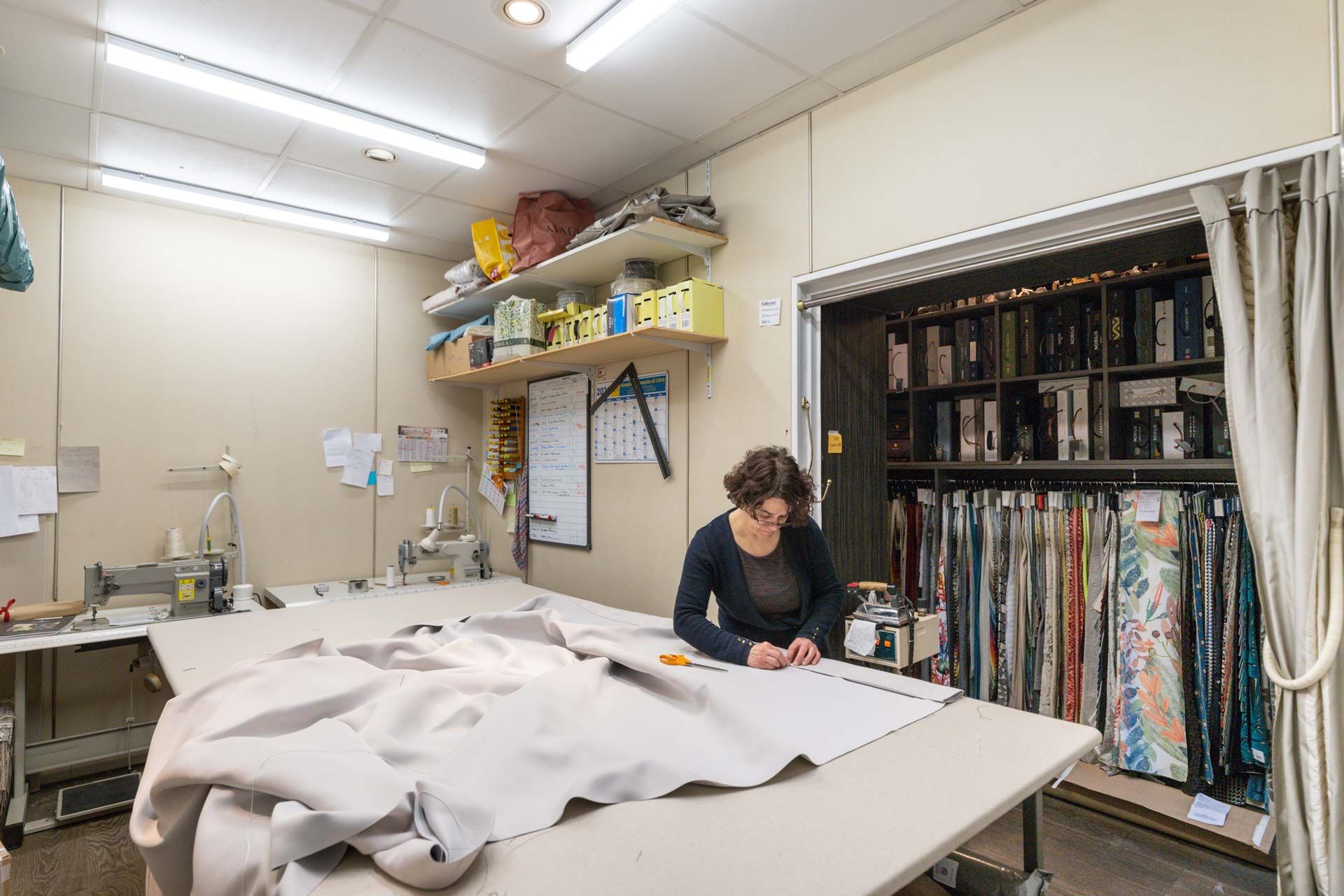 Une couturière/tapissière dans l'Atelier Garnero sur la confection d'un rideau