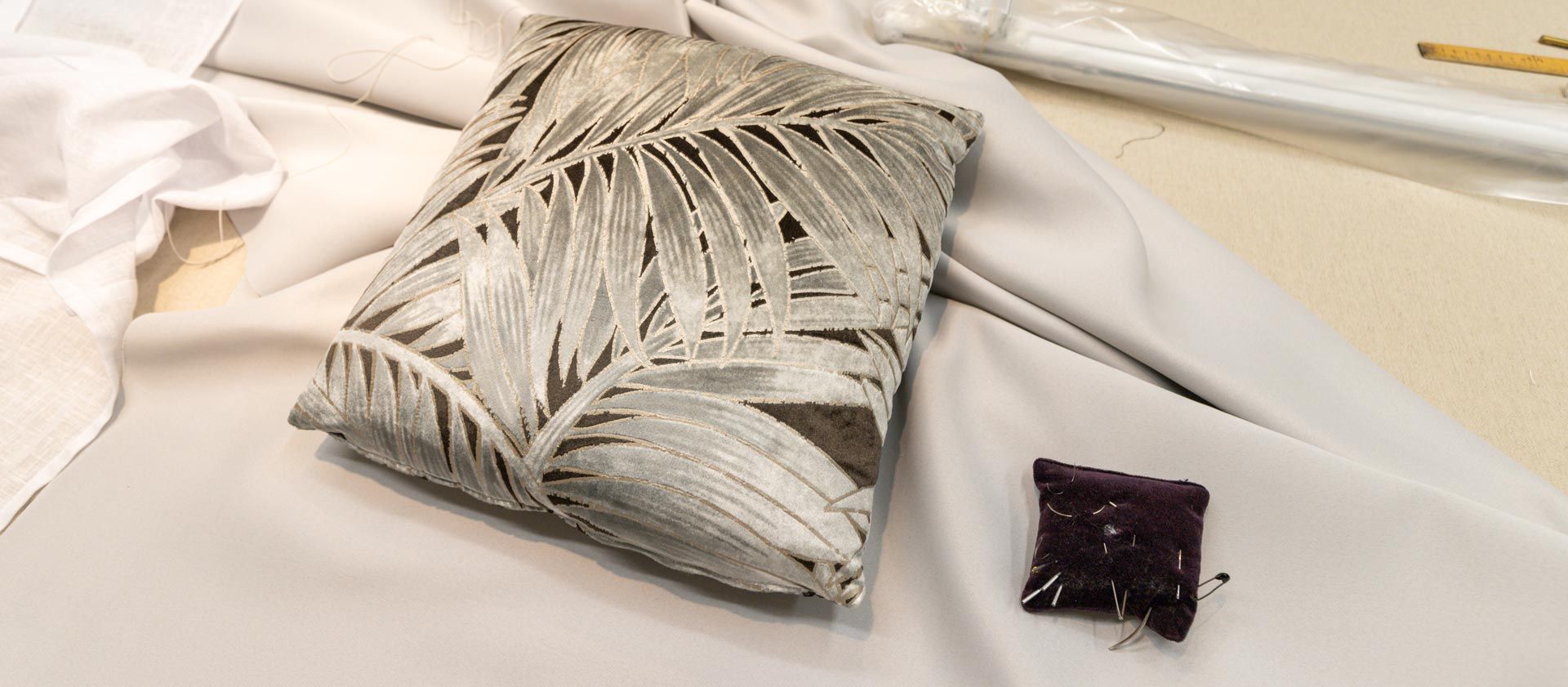 Un coussin personnalisé avec du tissu aux motifs végétaux posé sur une tenture