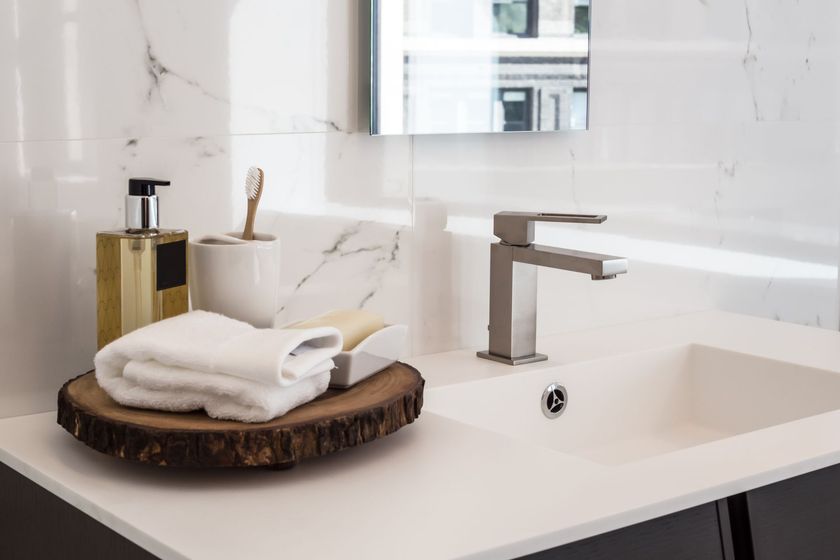 Lavabo de salle de bains moderne avec distributeur de savon, vasque et serviettes pliées sur un plateau en bois