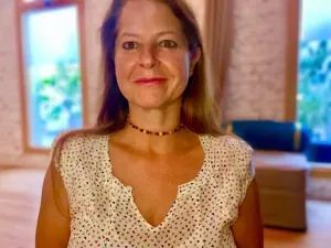 Una mujer con una camisa blanca de lunares sonríe a la cámara.