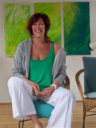 Una mujer con una camiseta verde y pantalones blancos está sentada en una silla.