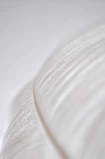 Un primer plano de una pluma blanca sobre una superficie blanca.