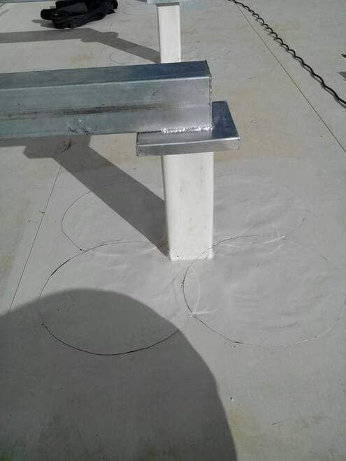 Una viga de metal reposa sobre una superficie de hormigón blanco.