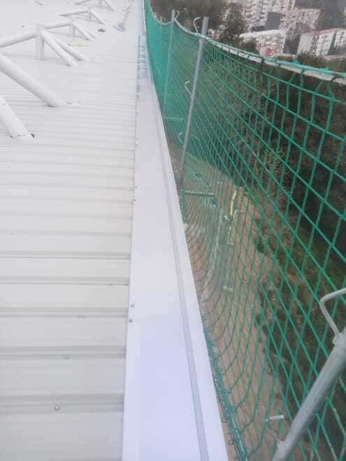 Una valla verde rodea un tejado blanco.