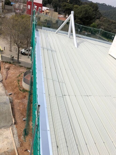Un techo blanco con una valla verde al costado.