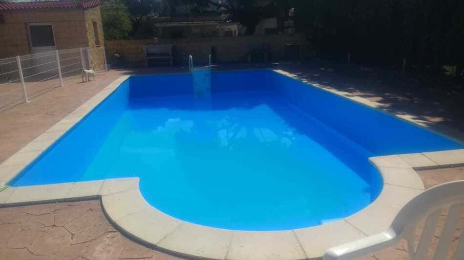 Una gran piscina azul está rodeada por una valla y sillas.