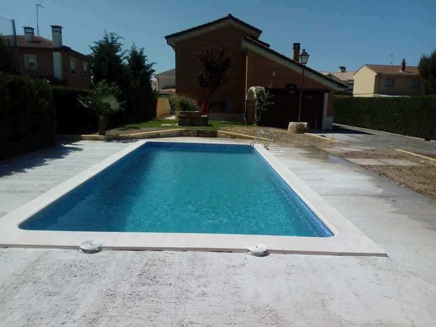 Una gran piscina con una casa al fondo.