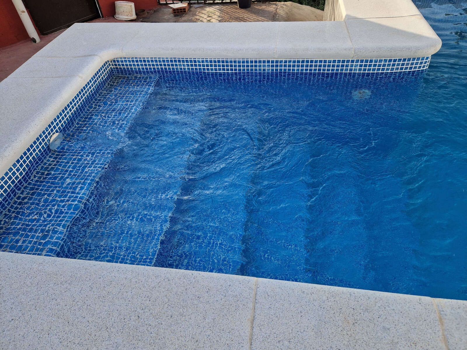 Una gran piscina con azulejos azules y escaleras.