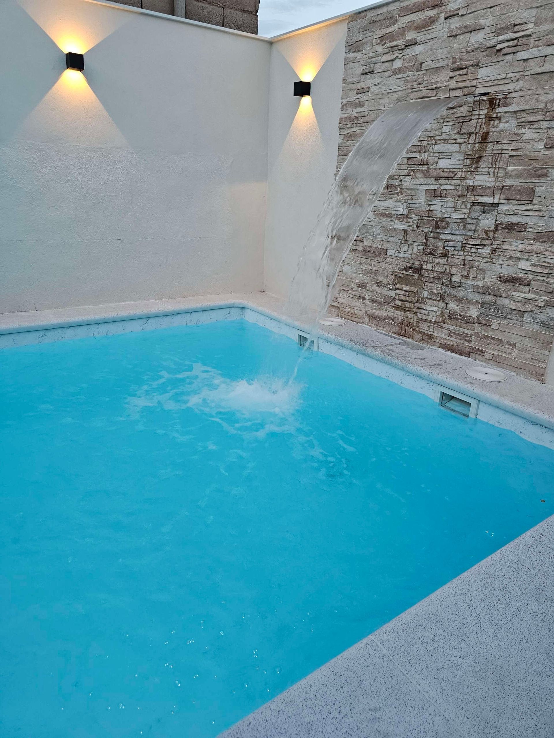 Una piscina con una cascada al fondo.