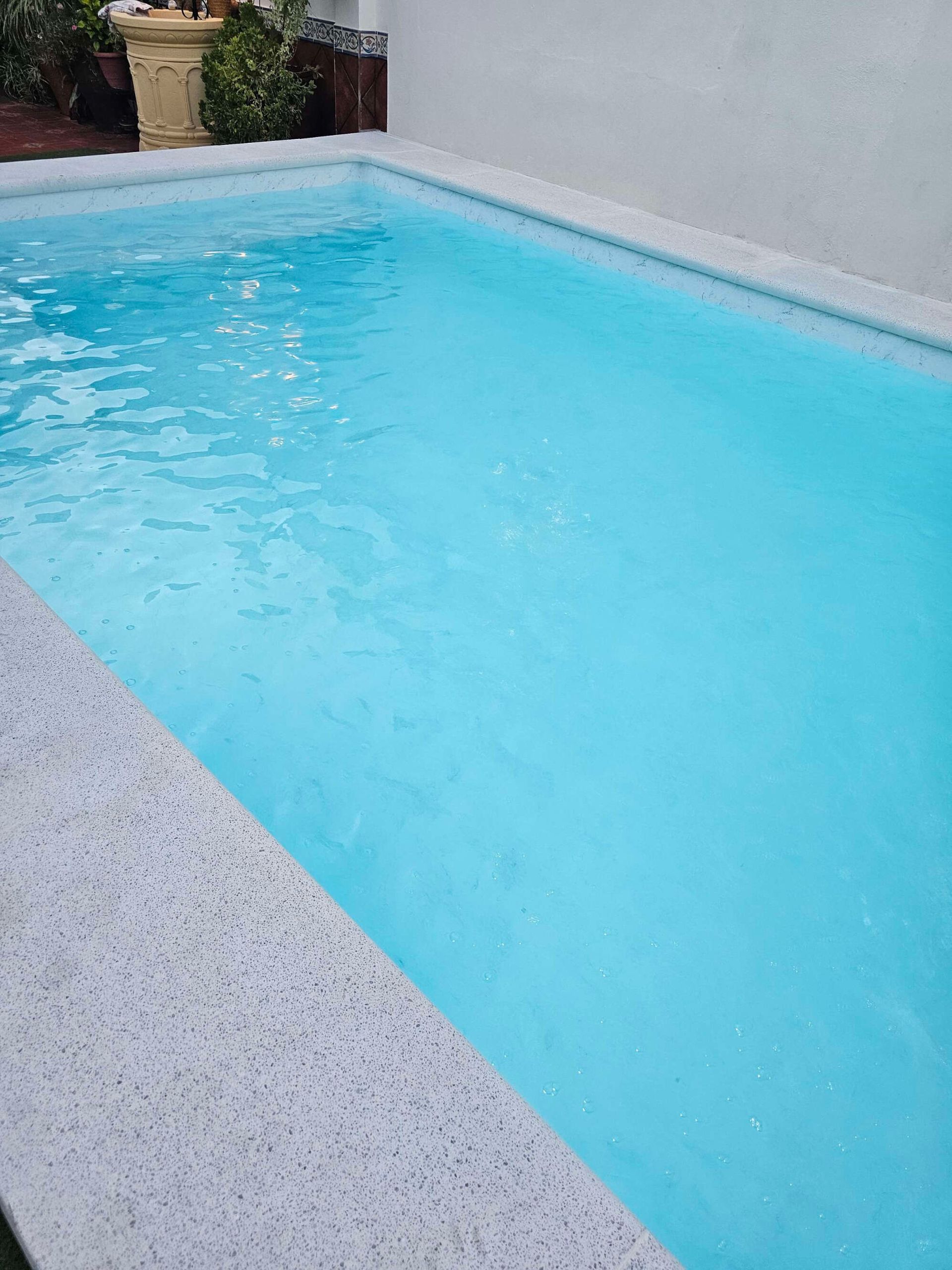 Una gran piscina llena de agua azul en un patio trasero.