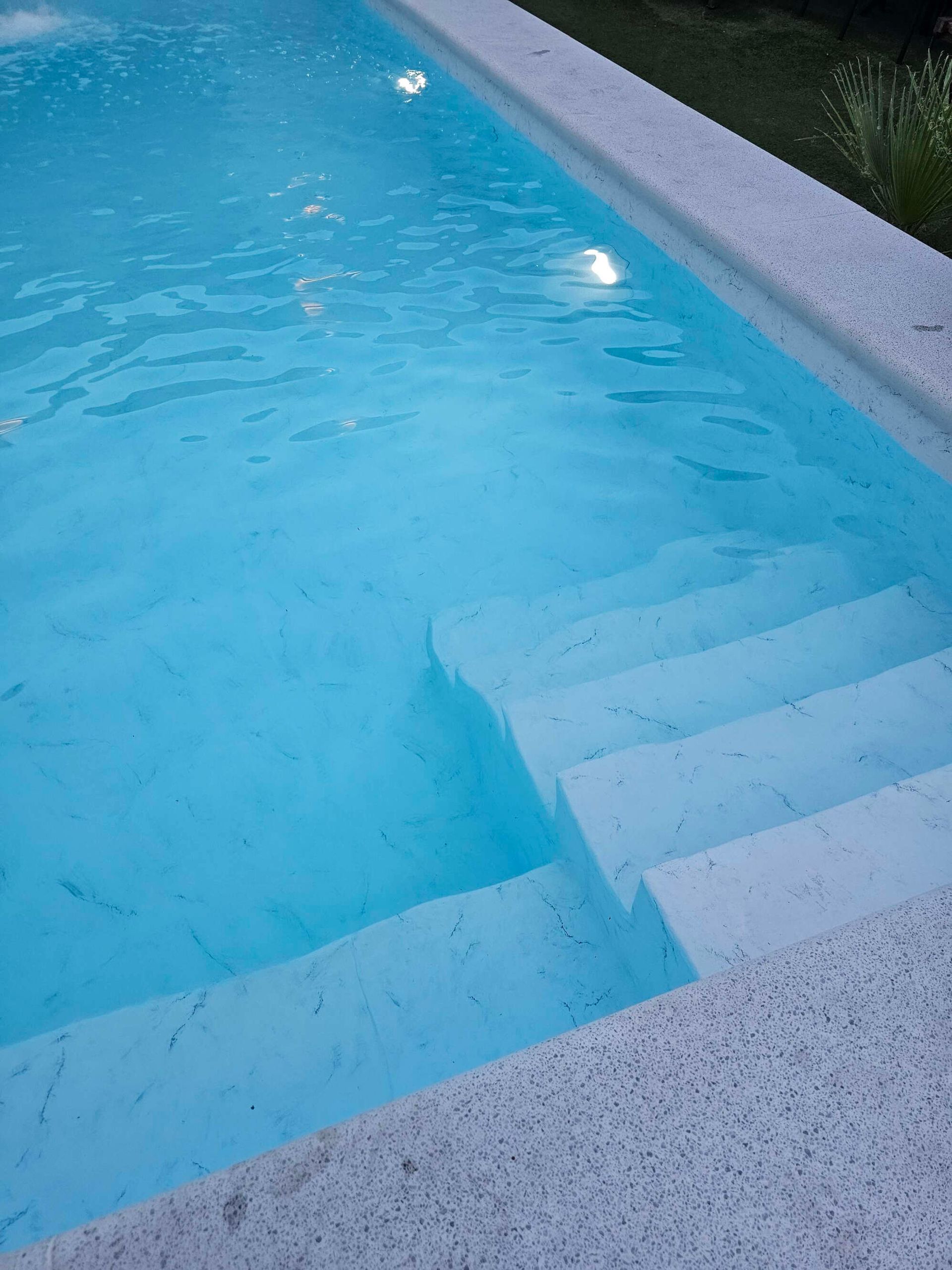 Una piscina con escaleras que conducen a ella y agua azul.