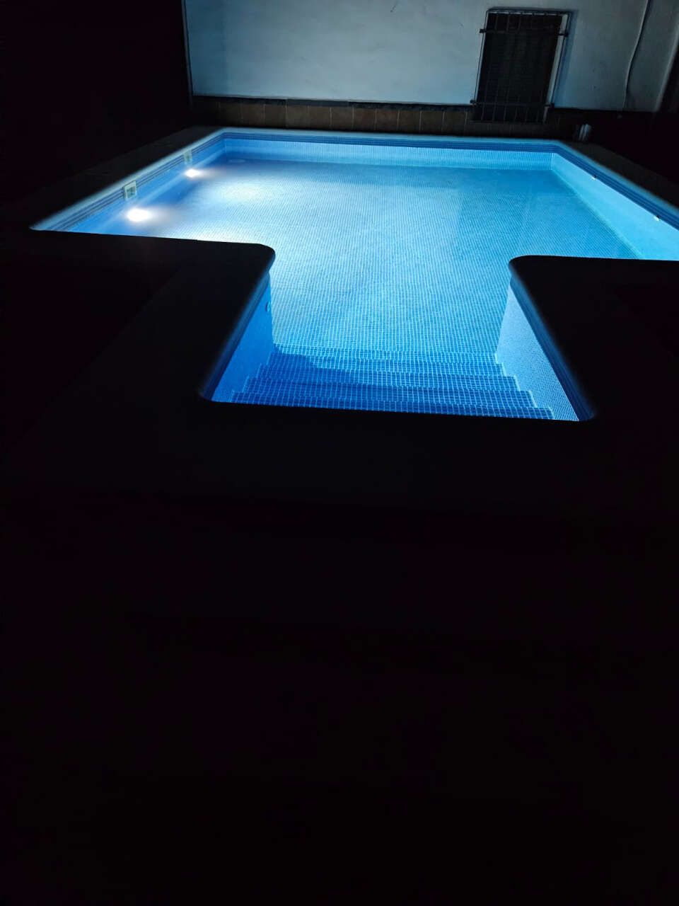 Una gran piscina está iluminada por la noche.