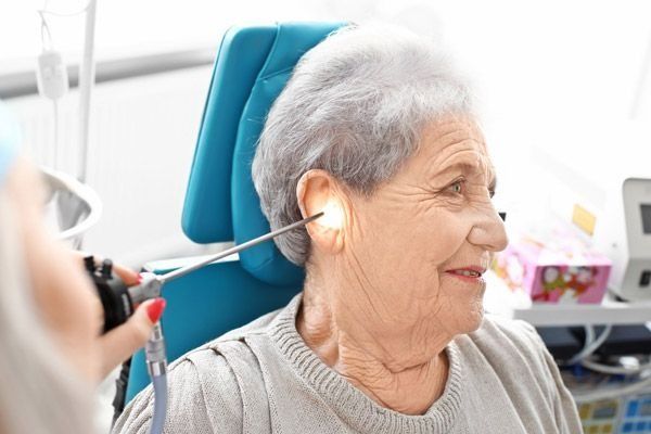 En un consultorio médico, un profesional de la salud utiliza un otoscopio para examinar el oído de un paciente.