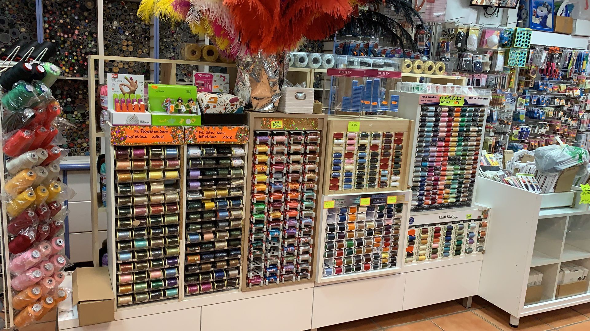Étagères remplies de fils de couture colorés et de produits de mercerie.