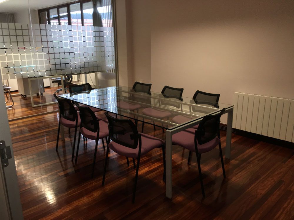 Una sala de conferencias con una mesa de cristal y sillas.