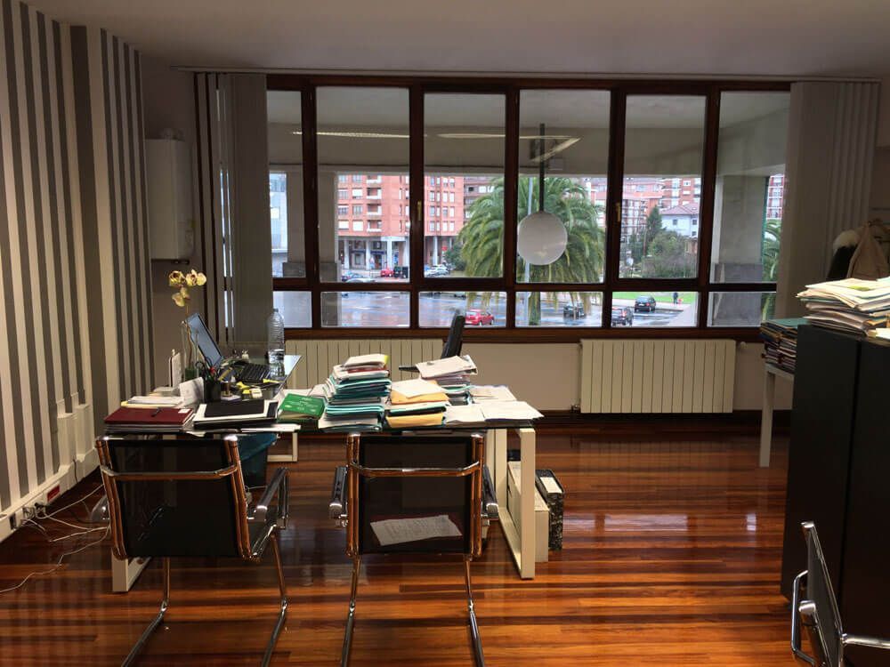Una habitación con muchas ventanas y un escritorio y sillas.
