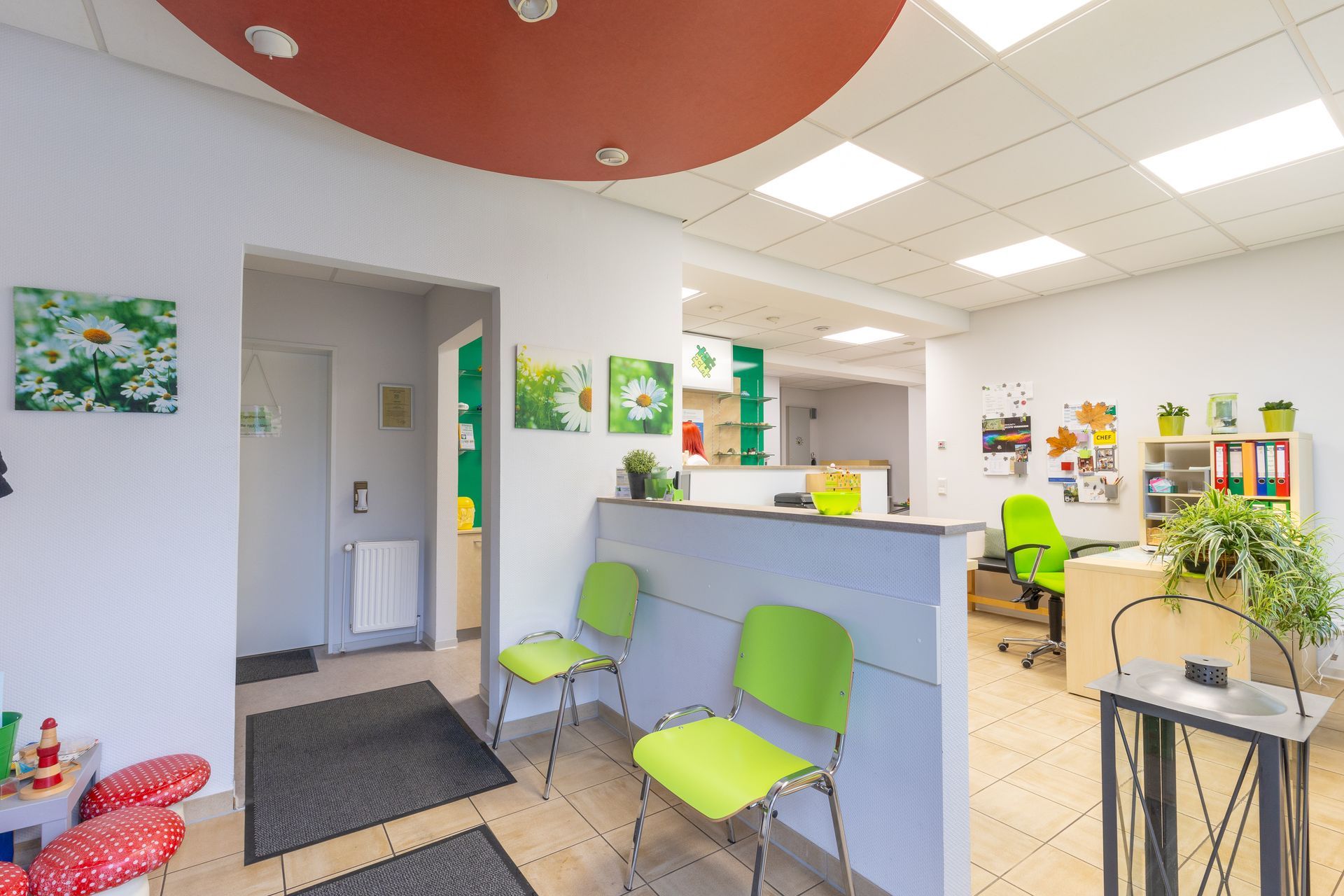 Ein Wartezimmer mit grünen Stühlen und einer roten Decke.