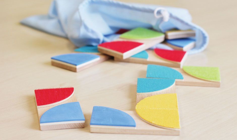 Eine Tüte mit bunten Puzzleteilen aus Holz auf einem Tisch