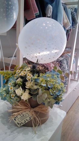 Arreglo floral con hortensias azules, globo blanco, en tienda.