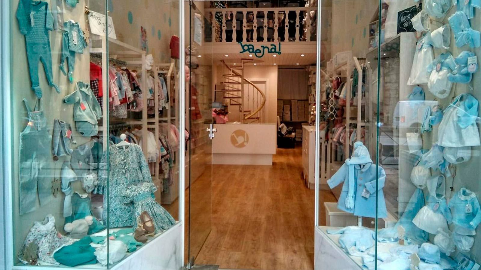 El interior de una tienda de ropa infantil con una puerta de cristal.