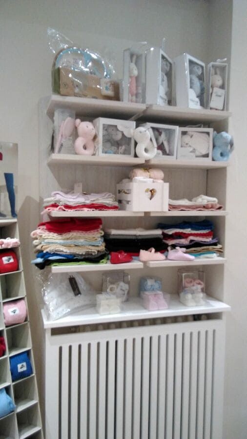 Una habitación con un radiador y estanterías llenas de ropa.