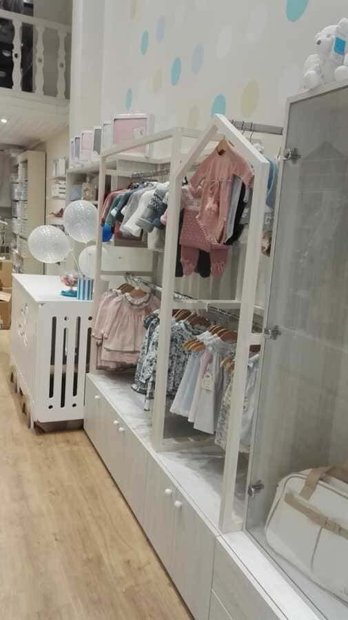 Una tienda de bebés llena de ropa y una cuna.
