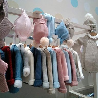 Una fila de ropa de bebé colgada en un perchero en una tienda.