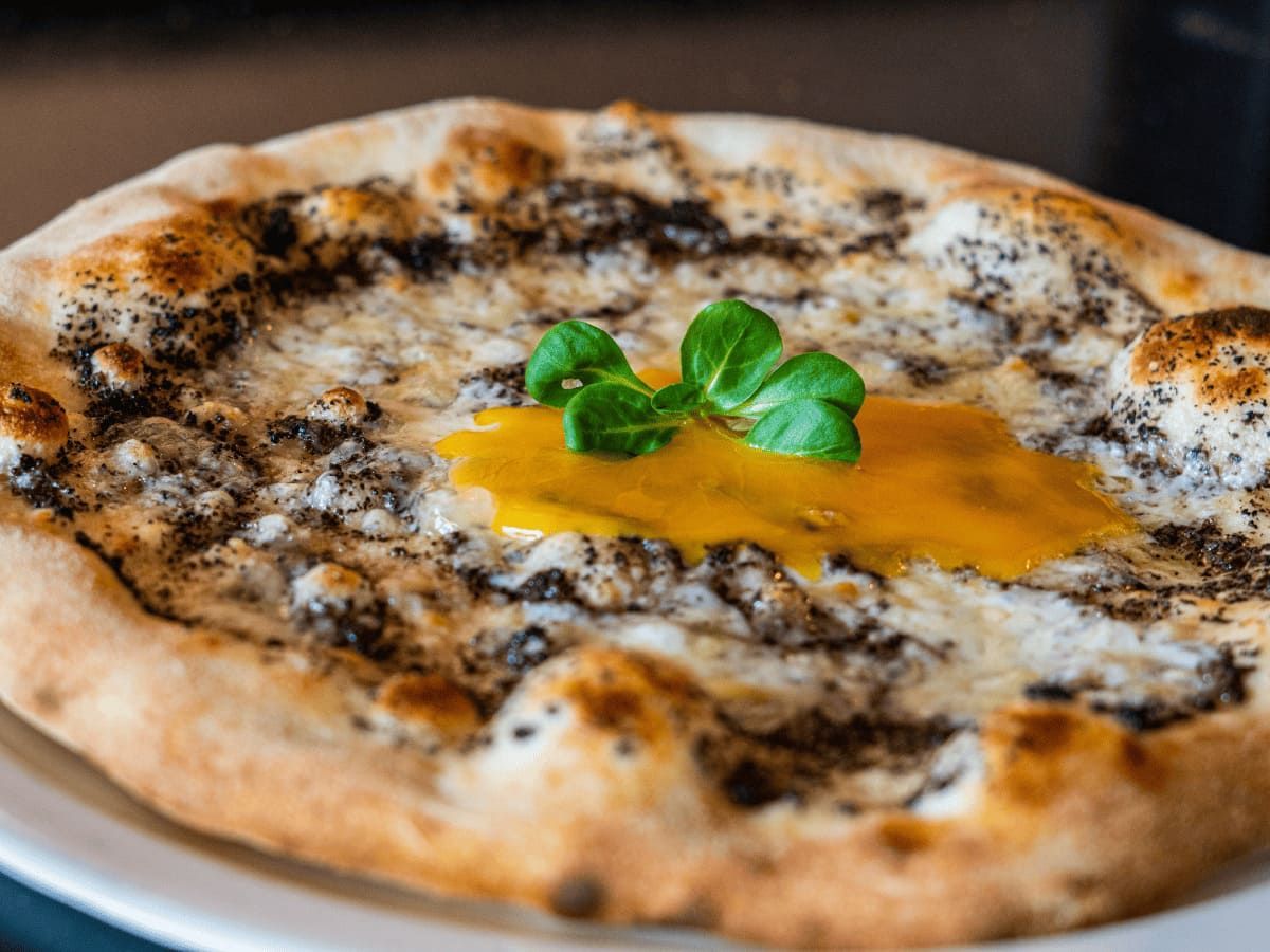 Una pizza con queso y albahaca en un plato blanco.