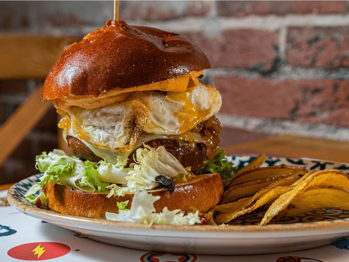 Una hamburguesa y papas fritas en un plato sobre una mesa.
