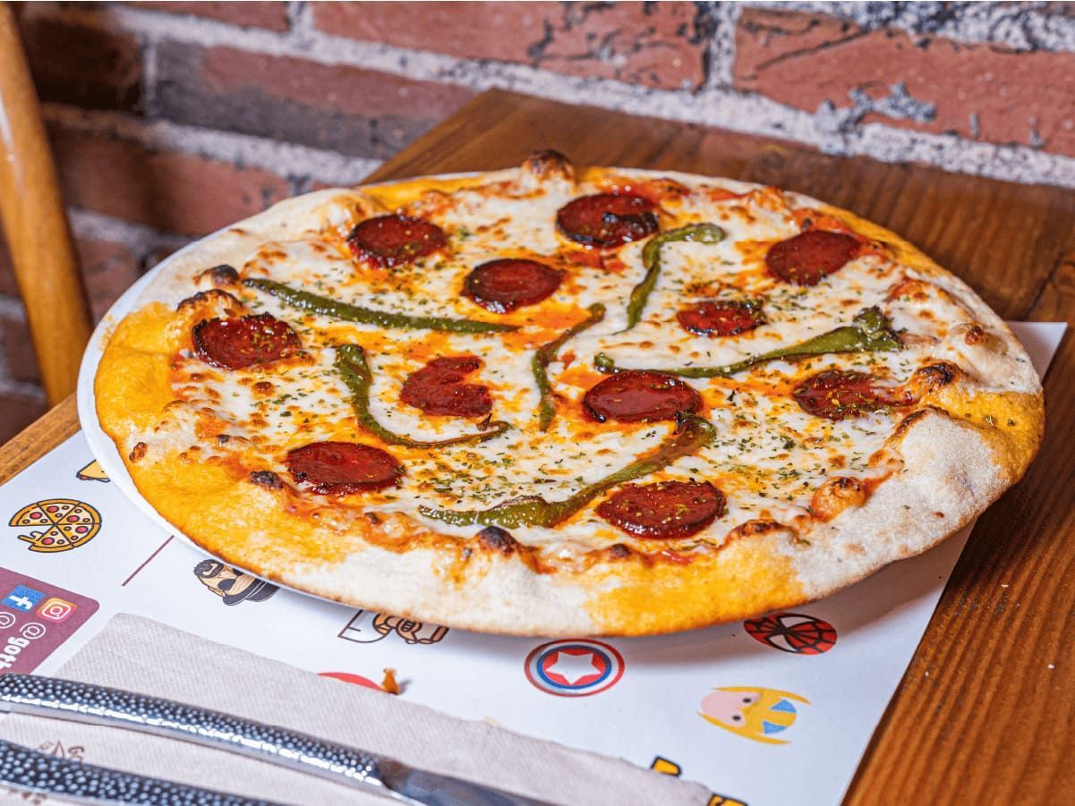 Una pizza con pepperoni y queso está sobre una mesa.