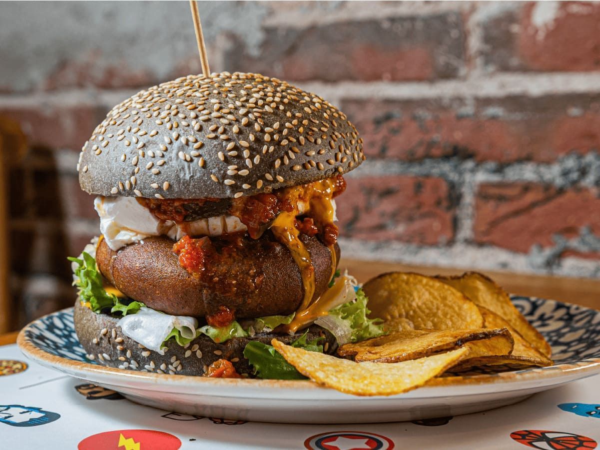 Una hamburguesa y patatas fritas están en un plato sobre una mesa.