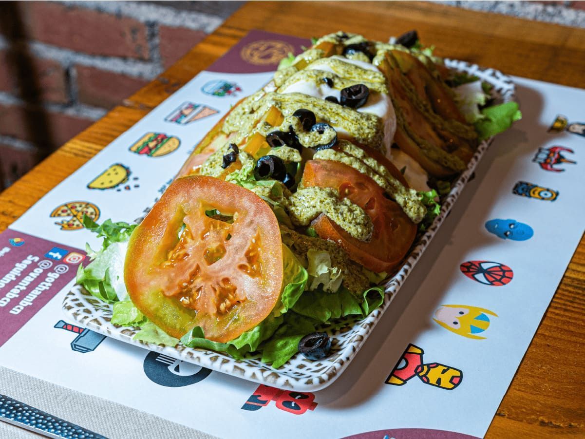 Un plato de comida con tomates y lechuga sobre una mesa.