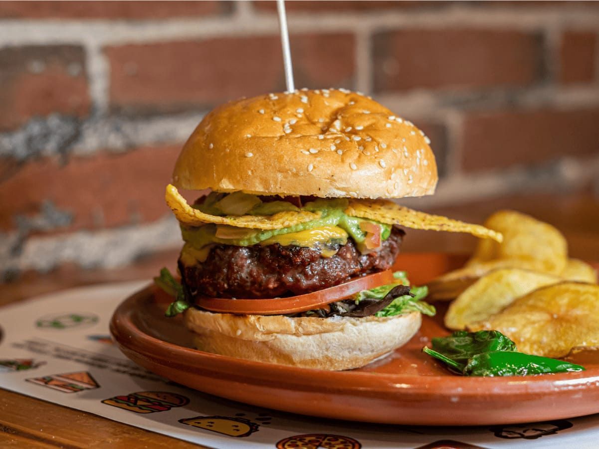 Un primer plano de una hamburguesa en un plato con patatas fritas.