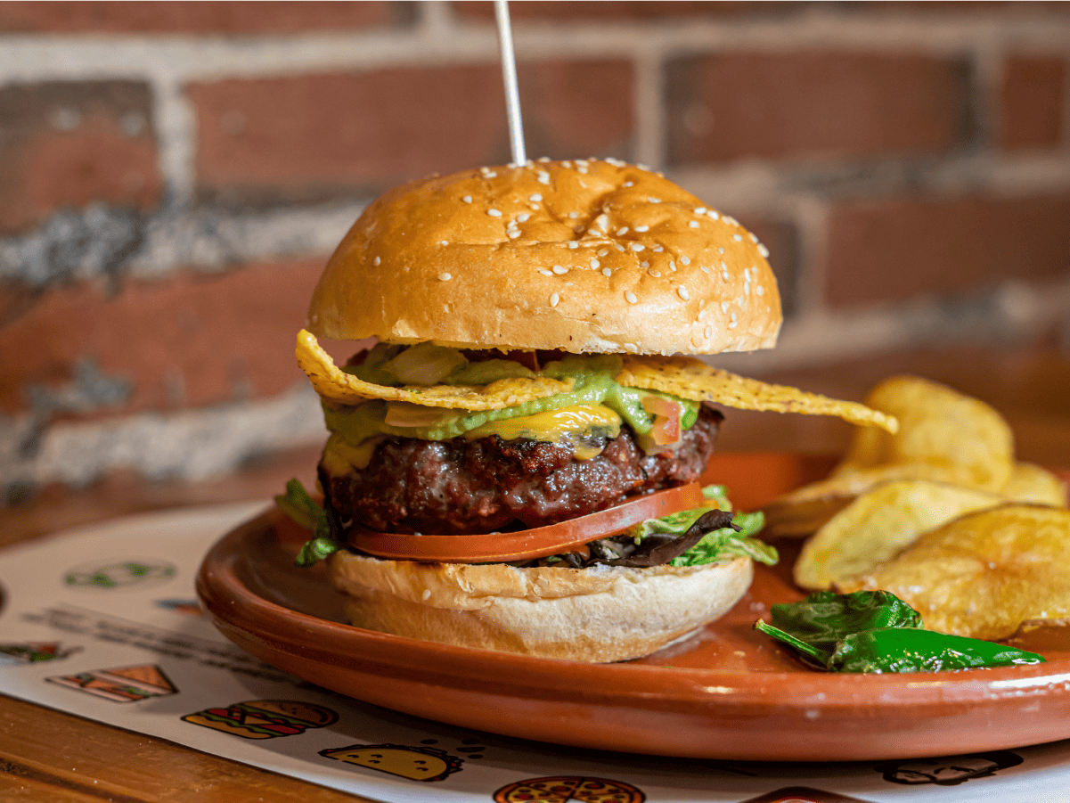 Un primer plano de una hamburguesa en un plato con patatas fritas.