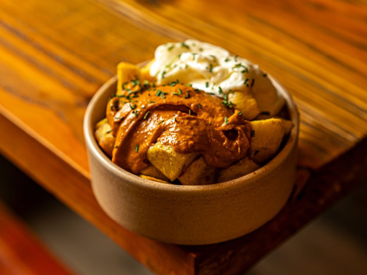 Un plato de comida con salsa y crema agria sobre una mesa de madera.