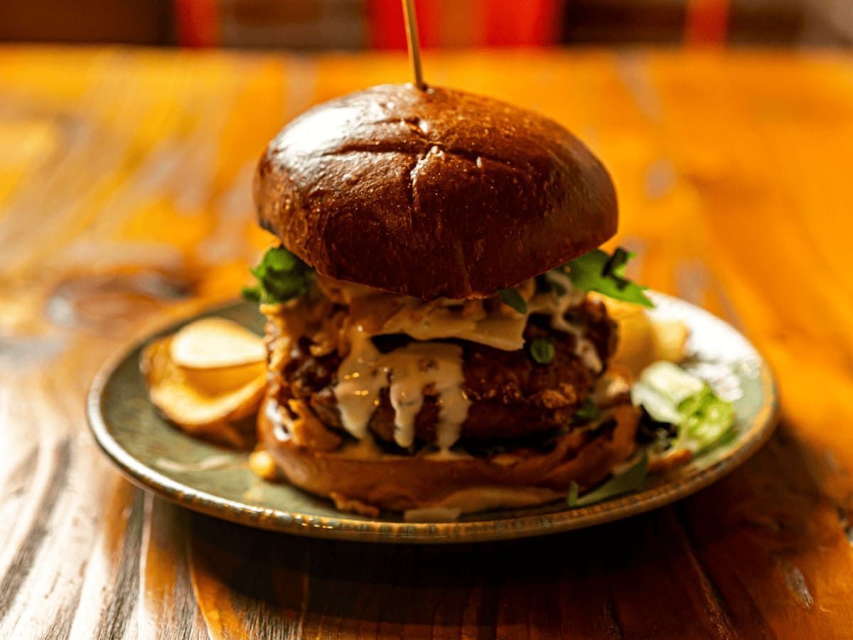 Un primer plano de una hamburguesa en un plato sobre una mesa de madera.