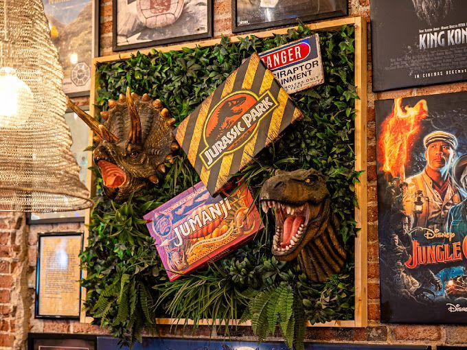 Una cabeza de dinosaurio está colgada en una pared junto a un cartel de Jurassic Park.
