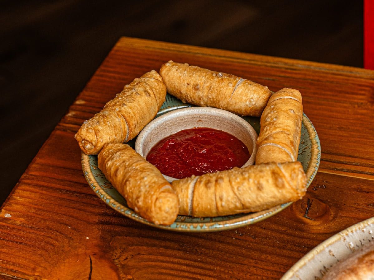 Un plato de comida con un tazón de salsa de tomate sobre una mesa de madera.