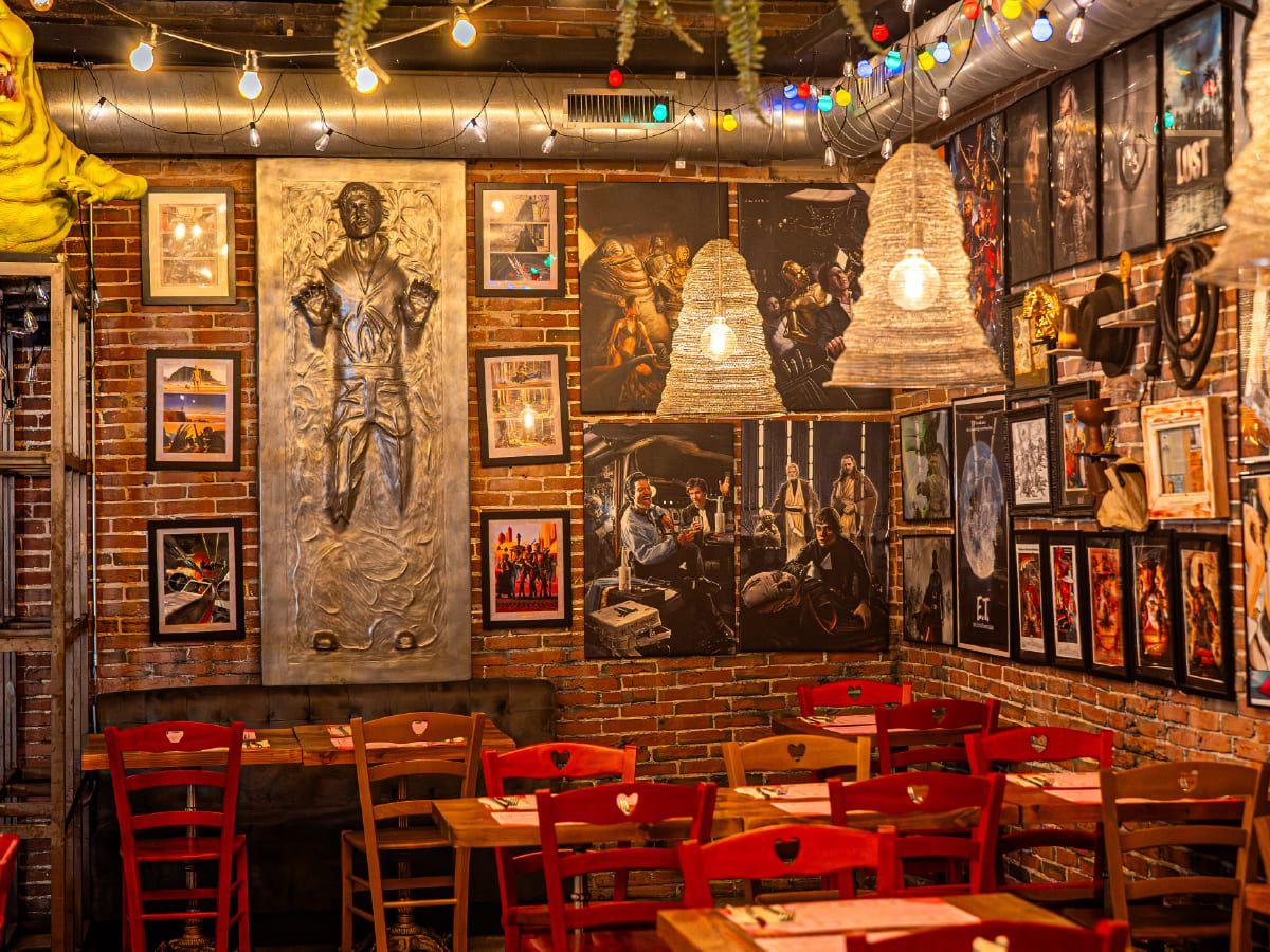 Un restaurante con muchos cuadros en las paredes y mesas y sillas.